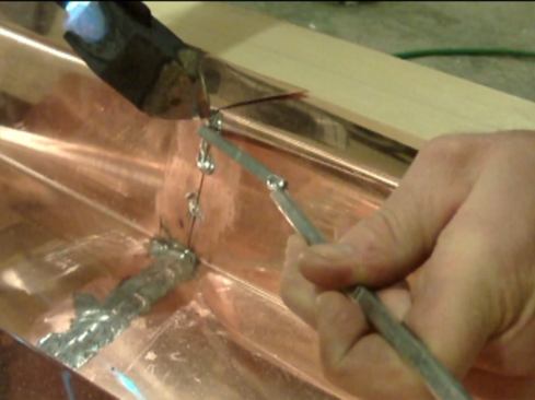 Vertical seams take more time. Also, it’s important to reduce the heat on the torch for vertical seam work. Start by applying flux on both sides, and again, “tack” the seam in several places with a spot of solder. Helpful tip: when a solder stick gets too short, splice it on to a longer one with the soldering iron.