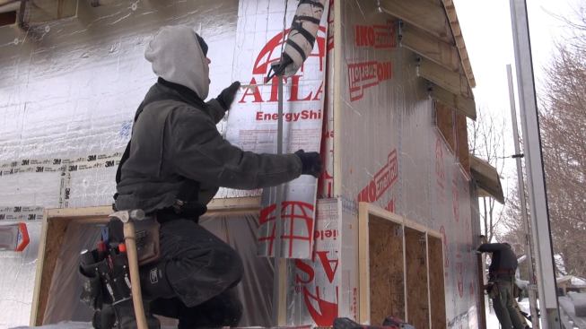 Mitchell places the last piece of foam at the top corner of one wall.