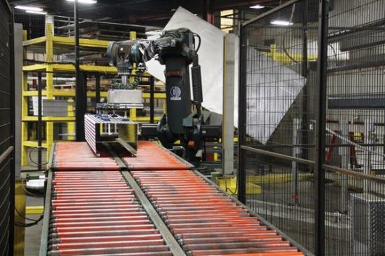 The aluminium piece coming down the rollers is part of a high side truck box. It has been placed there by the industrial robot that bent it to shape in a computer controlled robotic press brake. 
Click here to see the robot in action. A robot is performing this task because the pieces are heavy and the work is repetitive. It’s plant policy for people to avoid lifting anything heavier than 35 pounds.