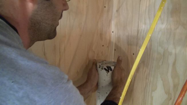 Project manager Mark Pollard seals the stubbed-up stack of the building’s sub-slab radon evacuation system in the basement.