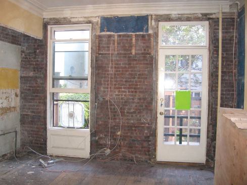 Plans called for replacing the window and the door in a rowhouse's structural back wall with a single three-panel slider. Note the exposed "American bond" brickwork: a single row of header bricks for every five courses of stretchers, a technique that ties the inner and outer wythes of brick together.