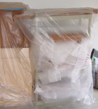 Cabinet doors, drawers, and removable end panels are stacked on inexpensive plastic shelves that are easily knocked down for transport to the job site. Corrugated cardboard or sheets of foam between items prevent scratches, and a covering of poly provides dust protection.