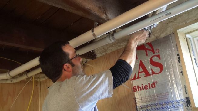 Mark Pollard spot seals the air gap at the top of the basement wall. The insulation contractors had held back from this area when they sprayed the band joist area, in order to avoid creating a mess.