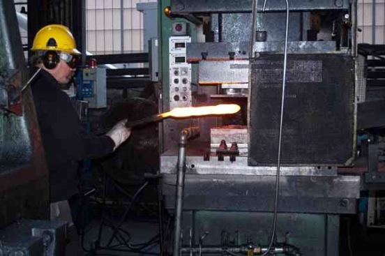 Seconds after forging, the rough parts are separated from the scrap metal on a trim press.