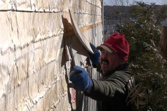 To start the job, a carpenter tears existing siding off the old house. Thirty-year-old existing housewrap shows the effects of age.
