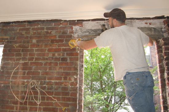 After removing the door and window, a carpenter begins chipping away enough of the inner wythe of brickwork over the openings to install a section of C10x20 steel channel, the first half of the header assembly.