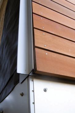 Outside corners received X-profile trim. The horizontal aluminum "belly band" was fastened to the sheathing with gasketed screws, which were driven into slightly oversized holes to allow for thermal expansion of the metal.