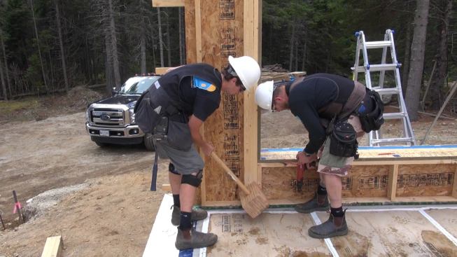 Wall sections are framed to exact tolerances in the shop, and need to be carefully placed in the field in order to maintain close tolerances during the set. Here, crew member George Reefer bumps a wall section toward the chalk line. Walls are pinned in place using powder-actuated concrete nails before being permanently secured with site-drilled anchor bolts.