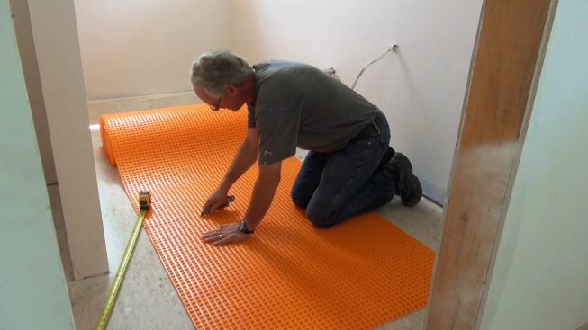 Boucher cuts a piece of Ditra to length with a utility knife.