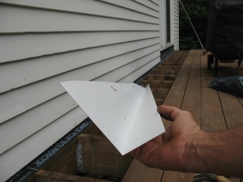 We fabricated aluminum L-flashing with a 5 ½-inch-tall wall leg—the tallest it could be without bumping up against the nails on the overlying siding course—and a 3-inch-wide joist leg. Along the edge of the joist leg, we bent a reverse hem to stiffen the metal and make it easier to handle when slipping it into place.