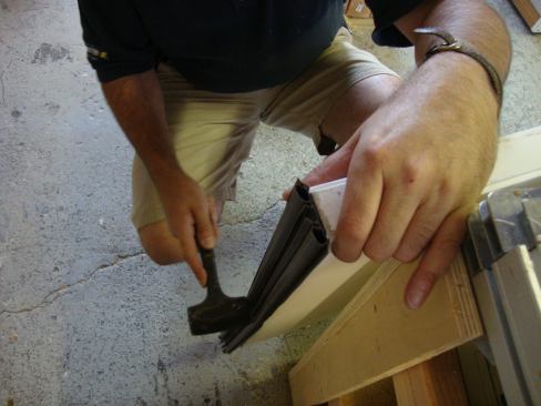 Greg gently taps the door sweep into the machined grooves.
