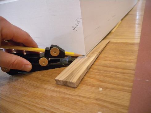 With the baseboard in position, I set my AccuScribe Pro scribing tool to the largest gap, then carefully run the scribe around the room to trace the floor contours onto the baseboard.