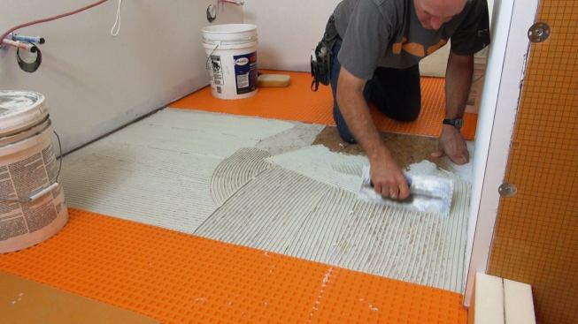 Boucher applies a measured amount of latex-modified mortar to the prepared subfloor using a three-eighths-inch toothed trowel.