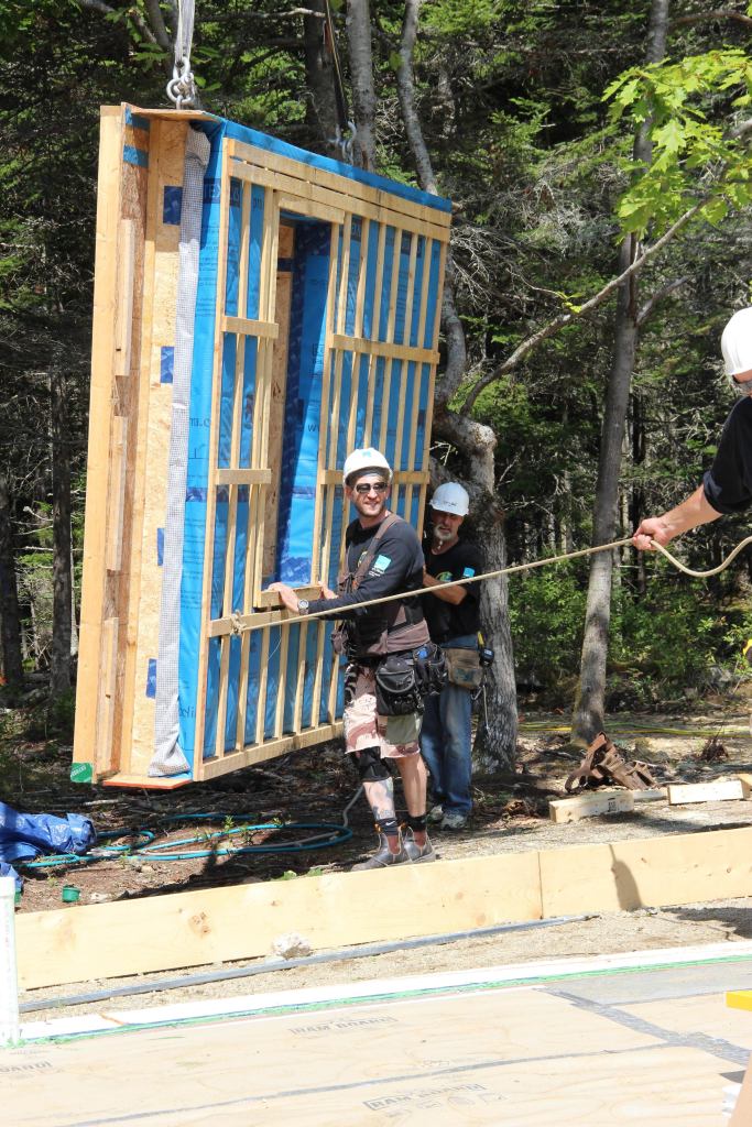 EcoCor owner, Chris Corson, guides a wall panel onto the slab.