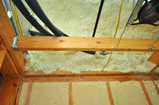 The rim-joist area and the wall above the rim joist are insulated to the roofline of the attached garage with 6 inches of closed-cell foam. This not only insulates the wall but also seals all penetrations.