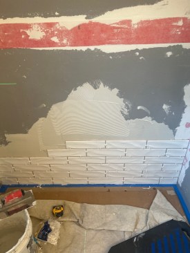 The new cultured-stone base was first cut to fit the new space with a hand-held tile saw equipped with a water spout. Note the flanges (along back edge and end), which are provided by the manufacturer and need to be secured to the edges of the base before it is set in thinset.