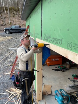 Using carefully placed 15-gauge stainless-steel nails, a crew member installs the preassembled jamb and casing sets.