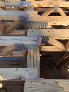 Where the gussets of overlapping joists touch, the crew inserts sill-seal foam to prevent squeaks.