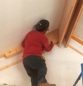 Workers use templates to confirm angles at both the top and bottom of the beam. They also transfer a mark from the template to the ceiling so that measuring the length of the panel is easier.