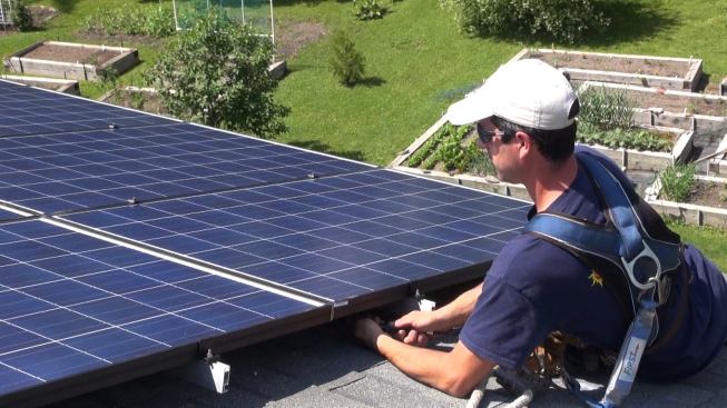With the circuit run to the disconnect switch at the inverter in the garage completed, project manager Brandon Bernard makes the final link, plugging the last module in the rooftop string to the home-run conductor on the roof. Now the circuit is energized and DC voltage will begin to flow to the inverter, which will make AC power for the house.