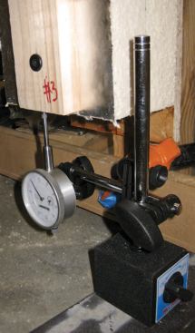 The wall-assembly samples were clamped in place to resist movement as the piston bore down on top of the strapping; a dial indicator on the floor measured the strapping's displacement as a video camera recorded the movement of the dial.
