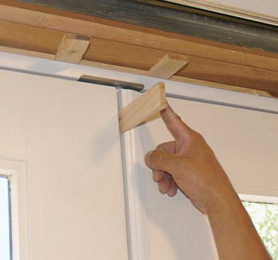 Temporarily shimming the gap between the two door sash keeps the unit from distorting or overcompressing the weatherstripping while the door is installed.