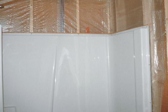 When a tub/shower unit is located on an exterior wall, the poly air barrier is installed before the tub goes in. To create a tight air barrier, the poly needs to be taped to the bottom plate of the wall.