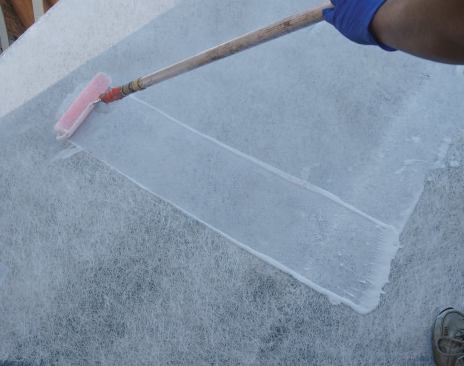 The cement is coated with acrylic resin. The resin soaks through and bonds the mat to the substrate, then cures to form a continuous waterproof membrane. It's important to lap the resin onto the vertical leg of the wall flashing.