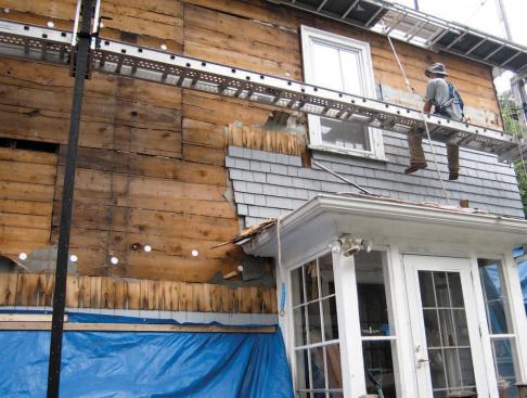 The crew stripped off the old cedar shingle siding, focusing on one side of the house at a time to protect the exposed walls and insulation from the weather.