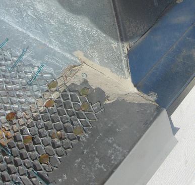 Where the deck meets the wall of the building, the gravel stop butts the L-shaped flashing and laps the Z-flashing below.