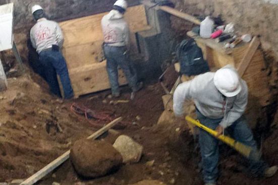 Workers excavate Brooklyn native soils by hand in the 100-year-old basement in preparation for forming and pouring center buttress sections. Corner buttresses are already in place.