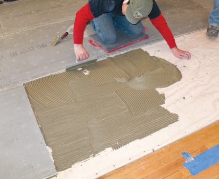 Carpenters troweled thinset onto a layer of 1/2-inch plywood installed over the AdvanTech sheathing.
