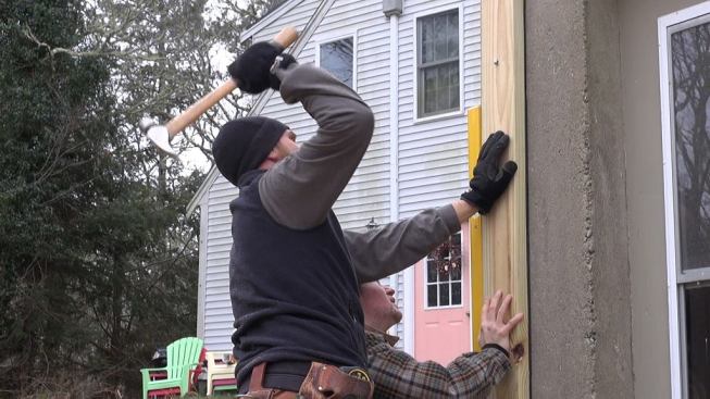 Hill drives a split-shank concrete anchor into the existing home’s concrete basement wall. With a correctly sized pilot hole, the split-shank fasteners are hard to drive into concrete, requiring a full swing with a framing hammer. Once driven, the fasteners are essentially impossible to remove, says Hill.