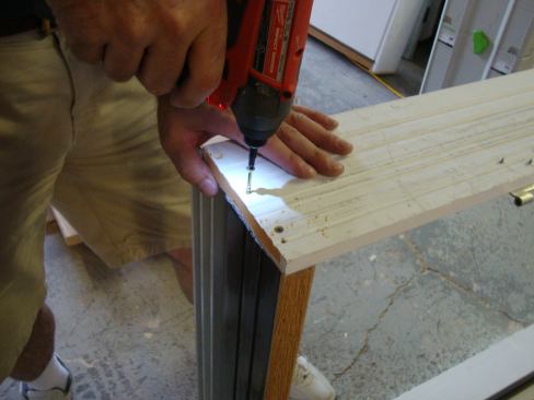 Greg drives 2-inch coated screws to secure the four corners of the frame.