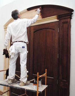 The author brushes the oil-based stain onto each section of trim.