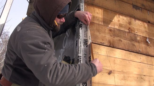 Creating the airtight barrier under the insulation on the house wall requires meticulous hand labor and attention to detail.