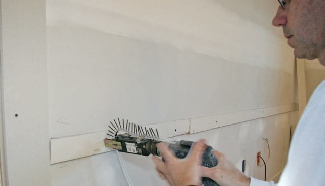 To begin, I snap layout lines, then screw (where there are studs) and glue (where there aren't) strips of 1/2-inch drywall cut to fit.
