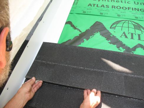 With this method the shingles lay on top of the flashing. The J-roll helps to divert water back onto the flashing where it drains down the slope. A bead of roofing cement can also help. Note that the J-roll might telegraph a hump through thinner 3-tab shingles.