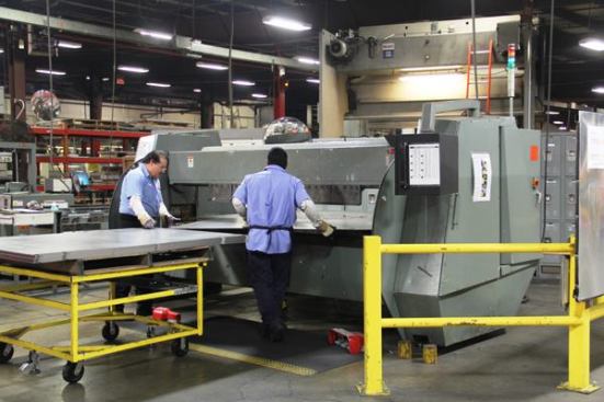 This piece of equipment is called a folding machine and is basically a mechanized metal brake. The operators position the piece on the work surface and the machine bends it to shape.