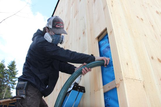 In Blue Hill, Maine, carpenter George Reefer blows insulation into a corner cavity on an EcoCor custom project. Superinsulated panels for this Passive House were pre-insulated in the panelizing shop, but some joints have to be insulated in the field.