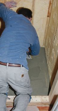 The weep drain was already in place. I checked that the floor was level, then nailed down a piece of 1/2-inch-thick Durock cement board in a bed of thinset.