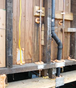 The author used one-component canned spray foam to seal plumbing and electrical penetrations through the walls, floor, and attic.