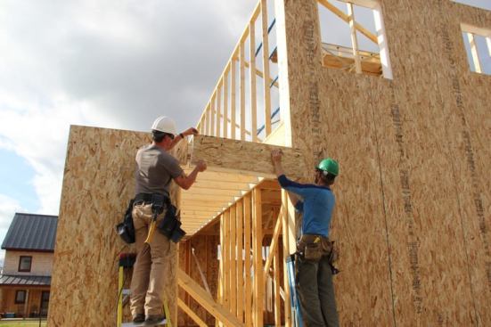 Carpenters fit the modified SIP piece into place after trimming to fit.