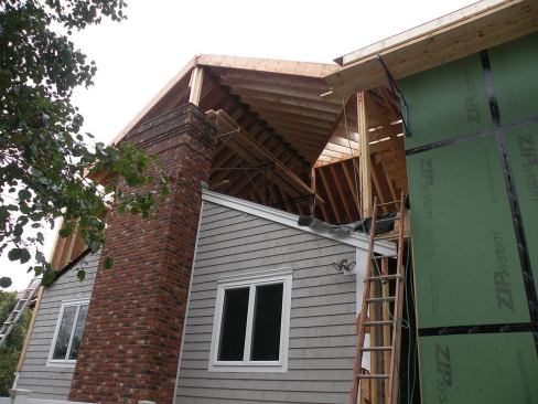 At this gable end location, the complex roof system is supported by two posts: one at the existing ridge, and one at the existing wall corner. The post bases are wrapped with Ice and Water Shield membrane to keep water out of the existing first story.