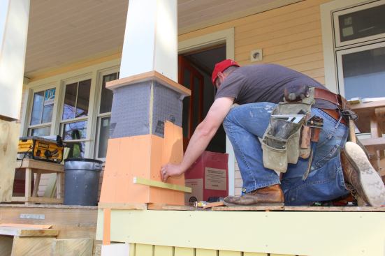 Fenton sets a cedar shingle in place on the post.