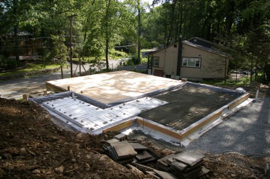 The original subfloor with its new, taped layer of plywood can be seen in the center of the photo. On the right, a 6-inch layer of stone dust—for thermal mass—covers 12 inches of foam.