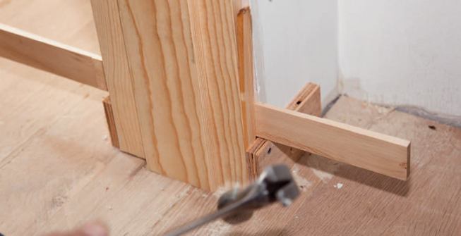 The author adjusts the latch jamb to the door, making sure that it makes contact with the stop along its entire length. Here, a shim behind the temporary retaining clip holds the jamb in position until the final screws are installed.