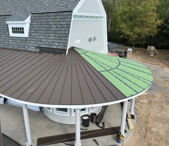 Pan installation began where the flat section of the porch shed roof ended (13). As the panels were installed, workers used a small set of roll benders to create the radius hem, then hand tongs to complete the joint.
