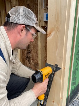 A carpenter uses a Speed Square to align the placement of 15-gauge stainless trim nails, giving thought to the fastener layout. Because all the pine material would be left to naturally age, the crew did not fill any nail holes. 