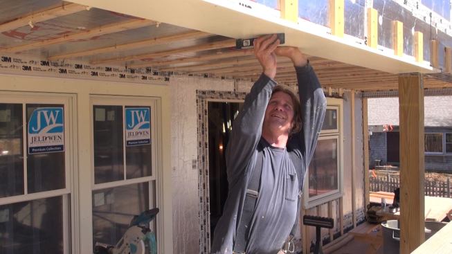Carpenter Dale Cunningham installs the front porch beam trim.